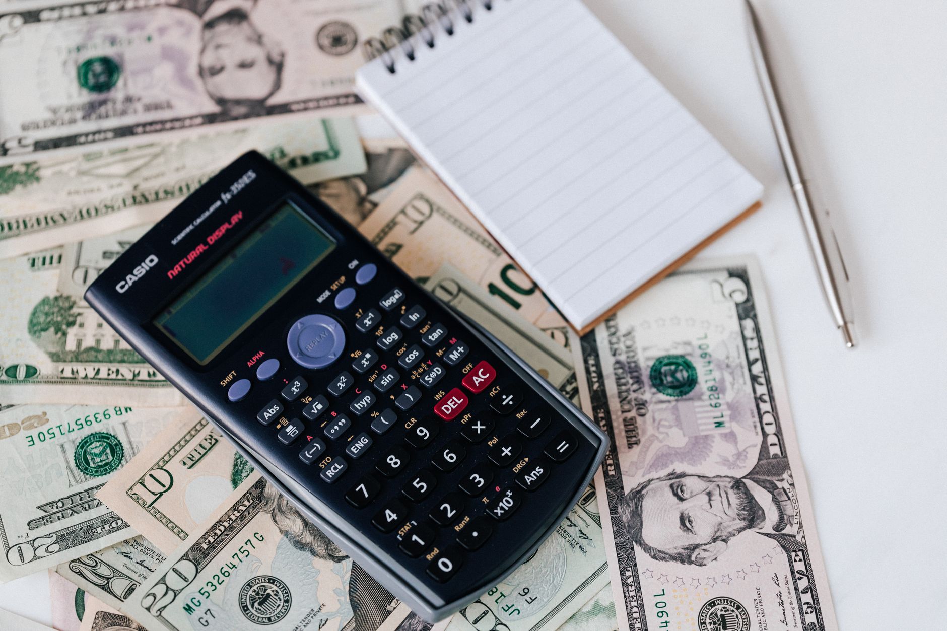 Calculator and notepad on US dollar bills, used to budget accelerated nursing program tuition