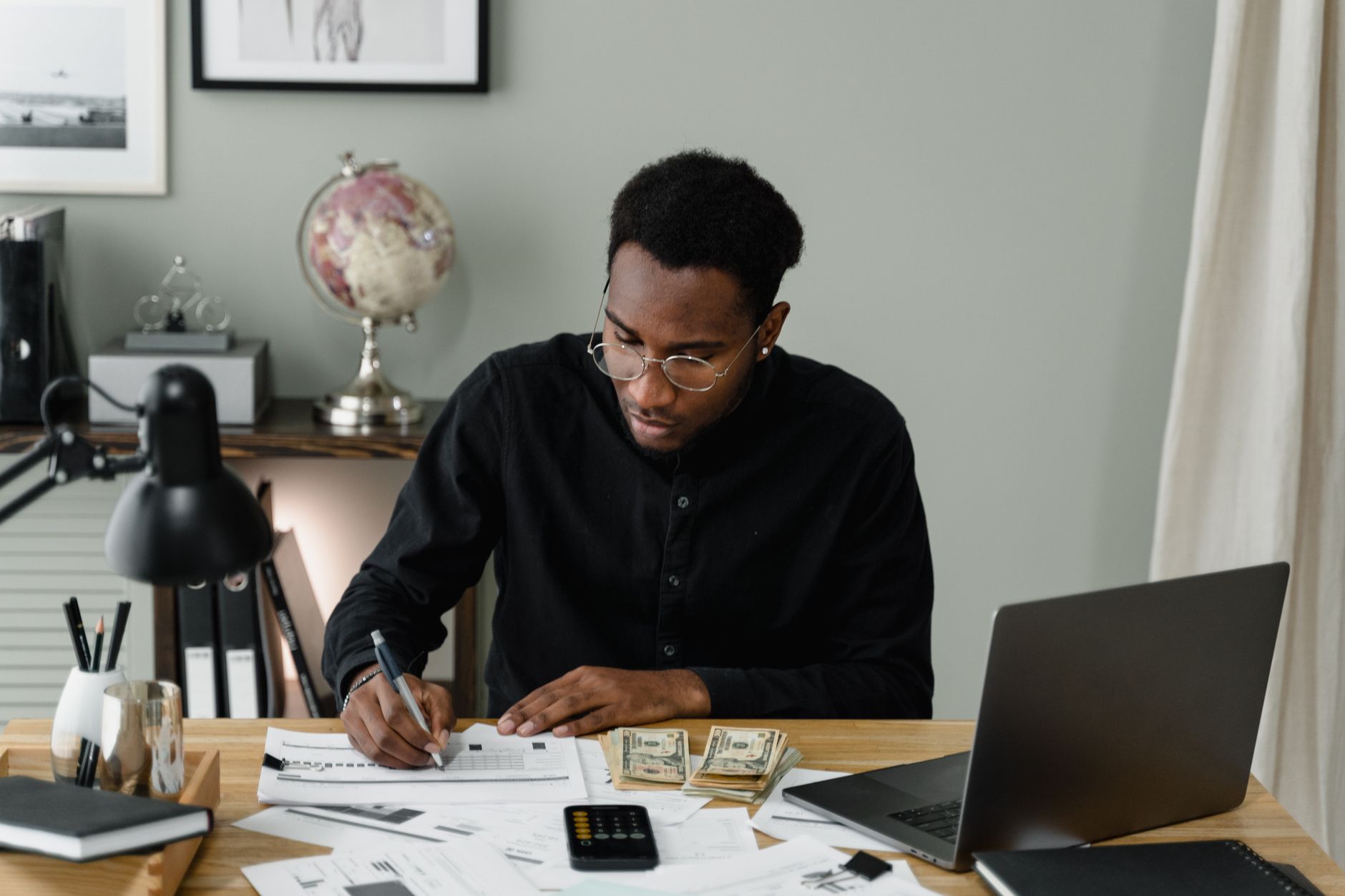 Nursing applicant budgeting for a possible HESI A2 retake with a calculator and laptop