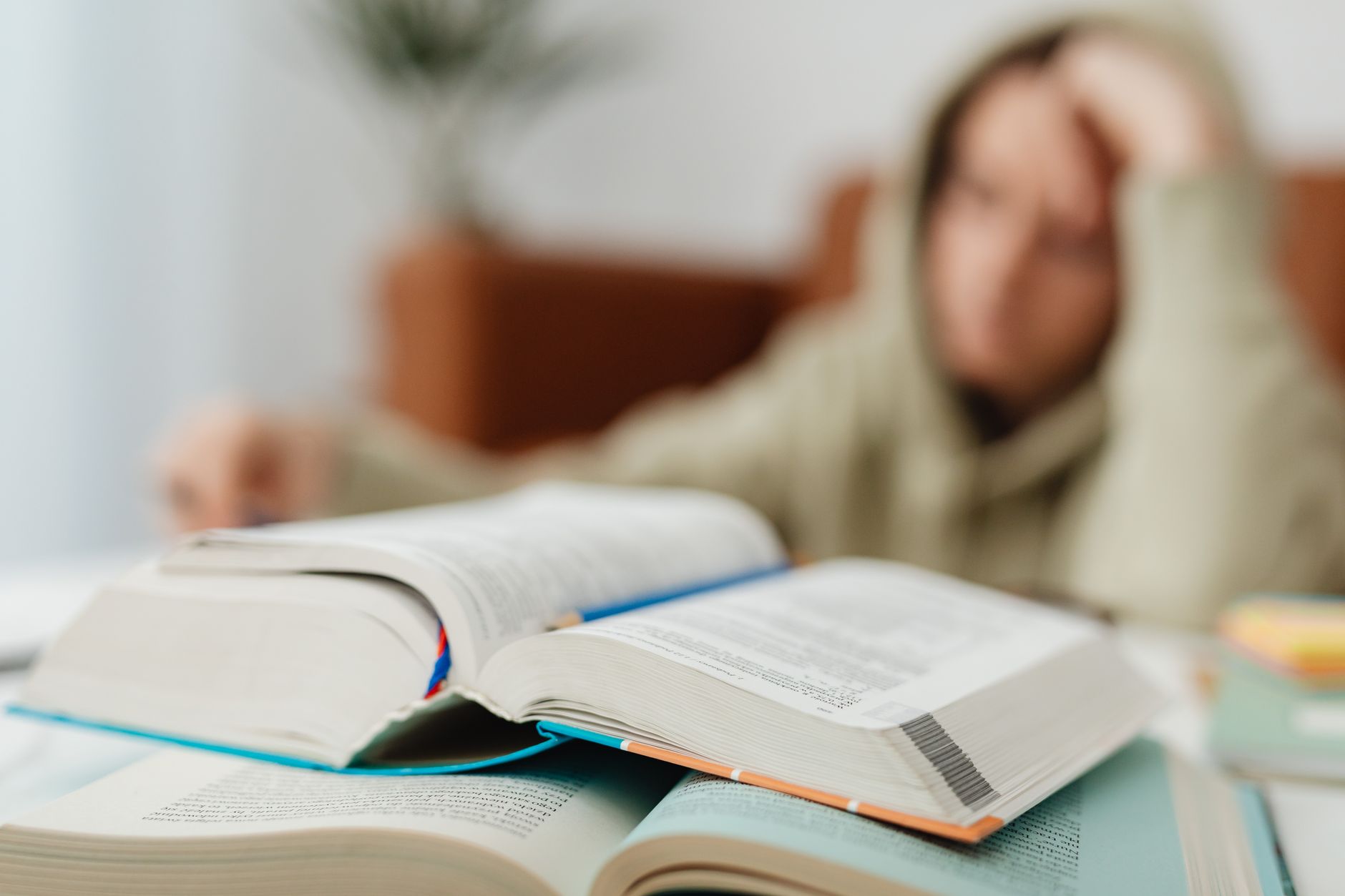 A nursing student studying a stack of pharmacology and pathophysiology notes late at night