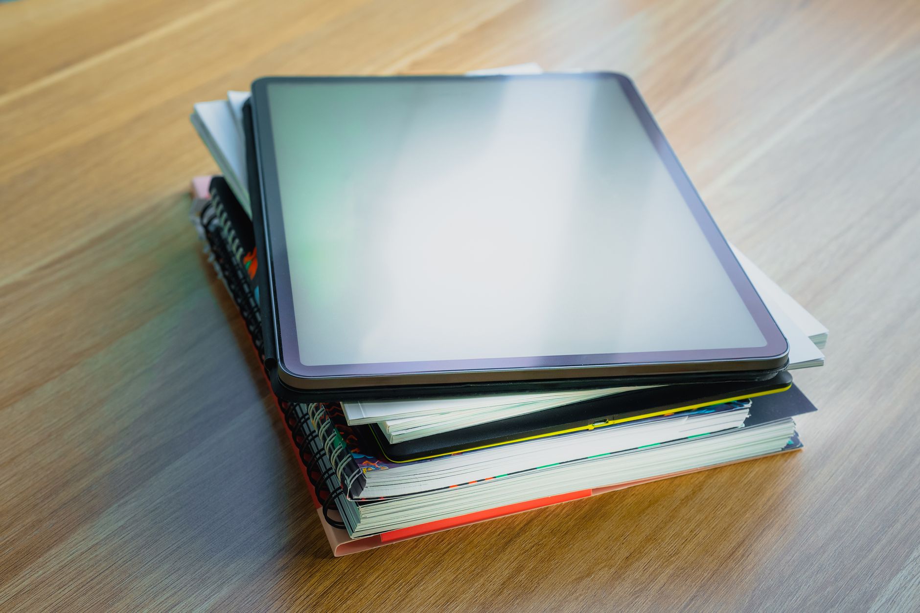 Core nursing textbooks and a drug reference guide stacked on a study desk beside a tablet